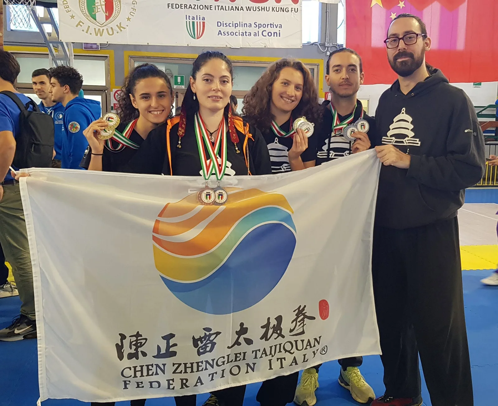 Samuele Contessa e i compagni di squadra con le medaglie al collo, dietro la bandiera della Chen Zhenglei Taijiquan Federation Italy