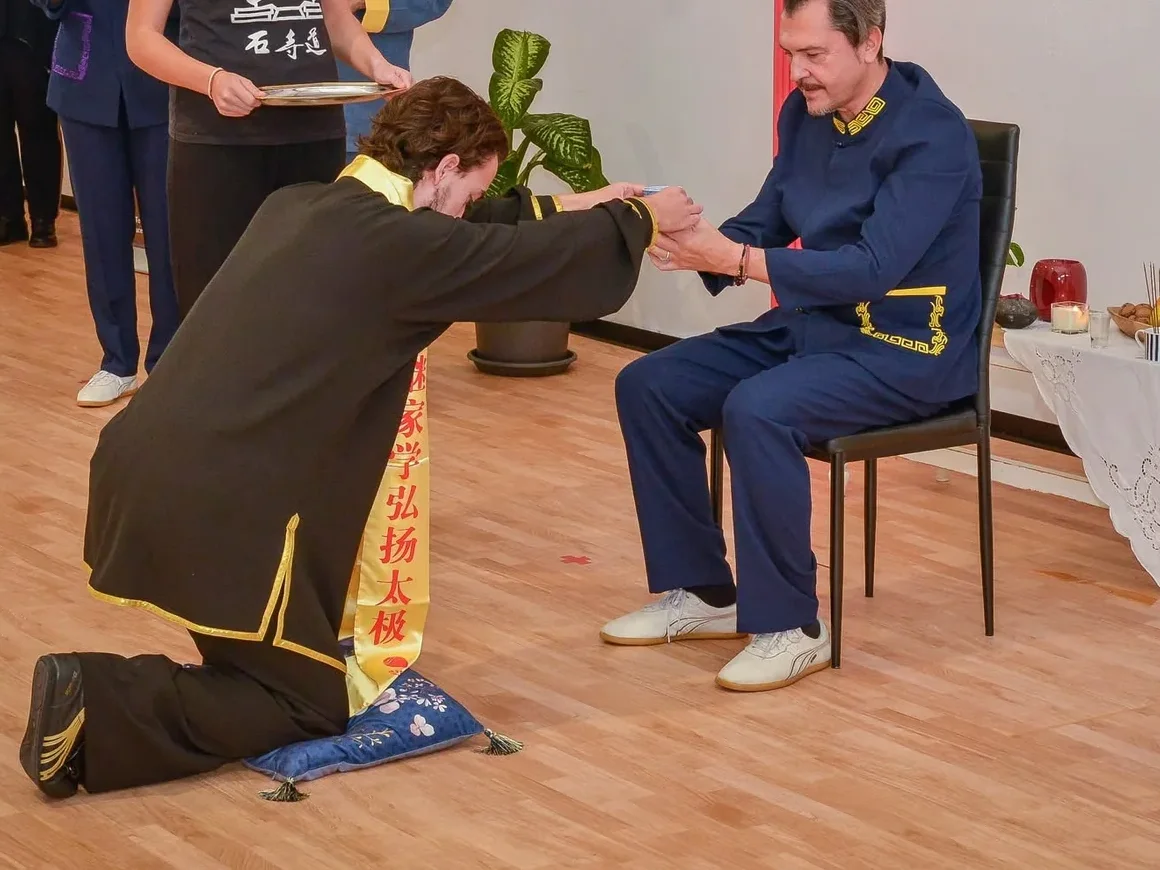 Samuele Contessa in ginocchio offre il tè al maestro Giuseppe Paterniti durante la cerimonia di discepolato
